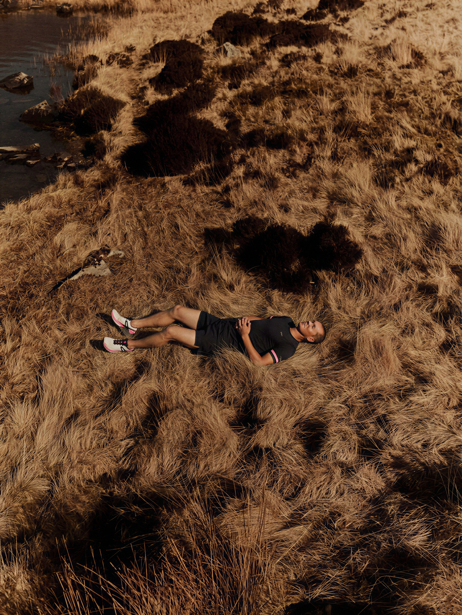 SunMer Day Shield High-Performance SPF50 Sun Stick — COSMOS Natural Certified. Person lying on dry grass near a body of water